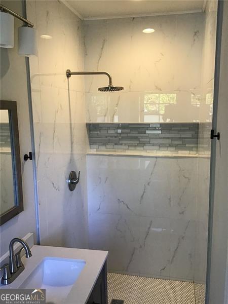 bathroom with a marble finish shower and vanity