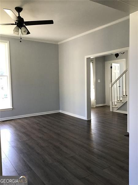 spare room with dark wood-type flooring, crown molding, and ceiling fan