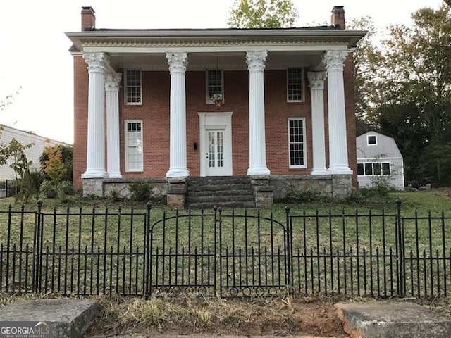 greek revival house with a chimney, brick siding, and a porch