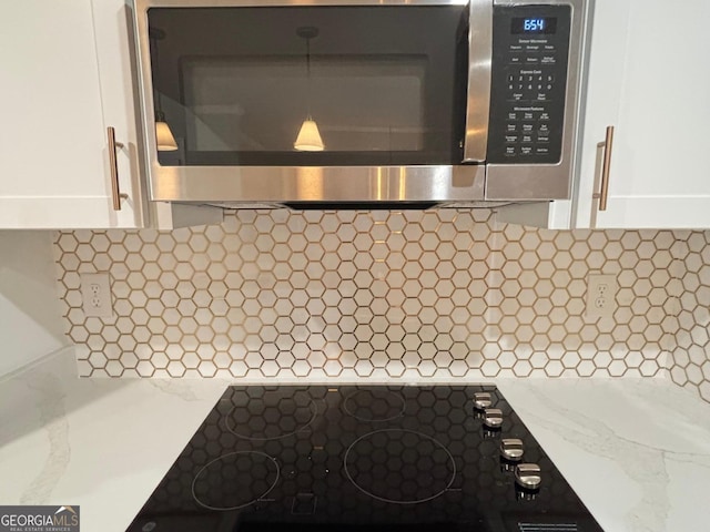 details with backsplash, black electric cooktop, and white cabinets