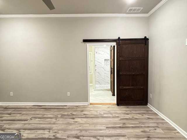 unfurnished room featuring a barn door, light hardwood / wood-style flooring, and crown molding