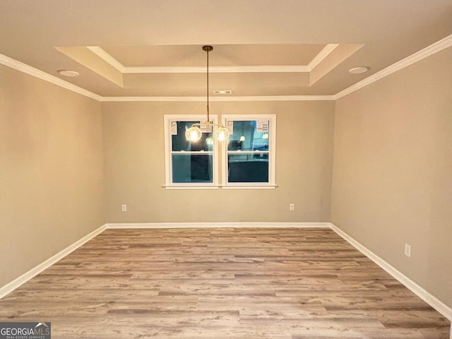 unfurnished dining area featuring hardwood / wood-style floors, a raised ceiling, crown molding, and a notable chandelier