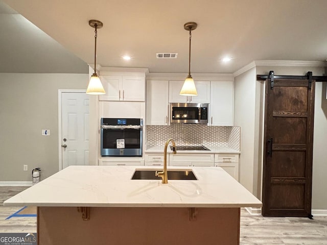 kitchen featuring a barn door, stainless steel appliances, white cabinetry, and sink