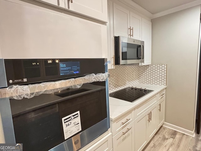 kitchen featuring white cabinetry, light hardwood / wood-style flooring, light stone countertops, and appliances with stainless steel finishes