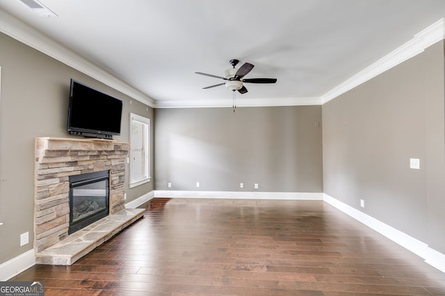 unfurnished living room with crown molding, ceiling fan, a stone fireplace, and dark hardwood / wood-style flooring