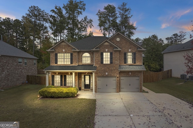 view of front of home with cooling unit, a garage, and a lawn