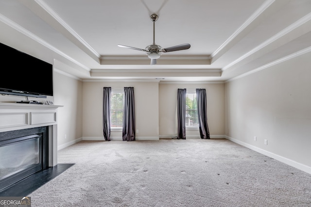 unfurnished living room with ornamental molding, a tray ceiling, carpet floors, and ceiling fan