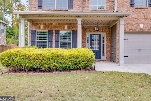 doorway to property featuring a porch, a yard, and a garage