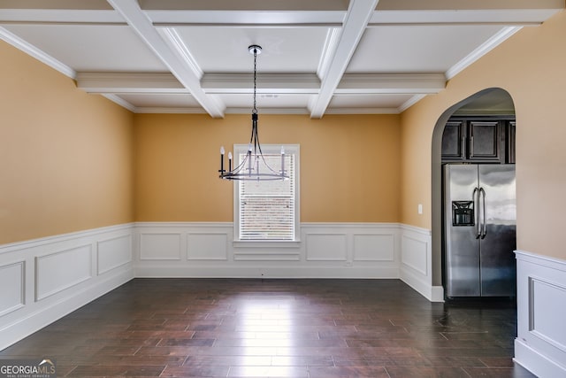 unfurnished dining area with coffered ceiling, dark wood-type flooring, beam ceiling, a notable chandelier, and ornamental molding