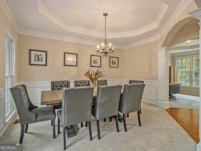 dining room with a chandelier, crown molding, a tray ceiling, and light hardwood / wood-style flooring