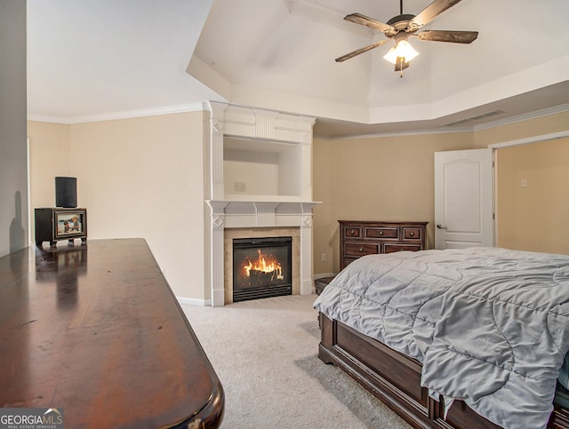 bedroom with ceiling fan, a raised ceiling, ornamental molding, and a tile fireplace