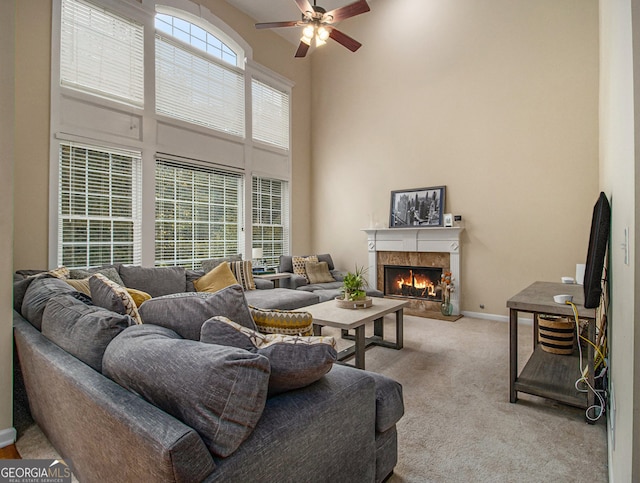 carpeted living room with ceiling fan, a towering ceiling, and a fireplace