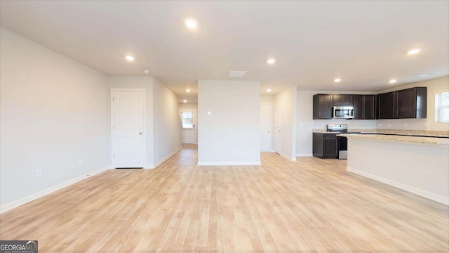 kitchen with light hardwood / wood-style floors, light stone countertops, a healthy amount of sunlight, dark brown cabinetry, and stainless steel appliances