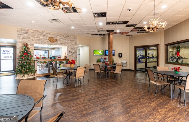 dining space with a notable chandelier, dark hardwood / wood-style flooring, and a drop ceiling