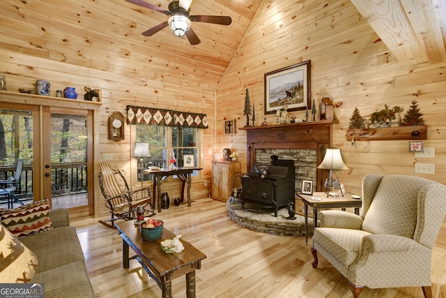 living room featuring ceiling fan, light wood-type flooring, a wood stove, and wood ceiling