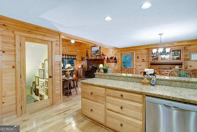 kitchen featuring wood walls, stainless steel dishwasher, and light stone counters