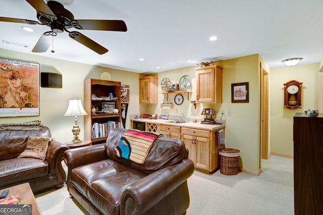 living room featuring light colored carpet, ceiling fan, and sink