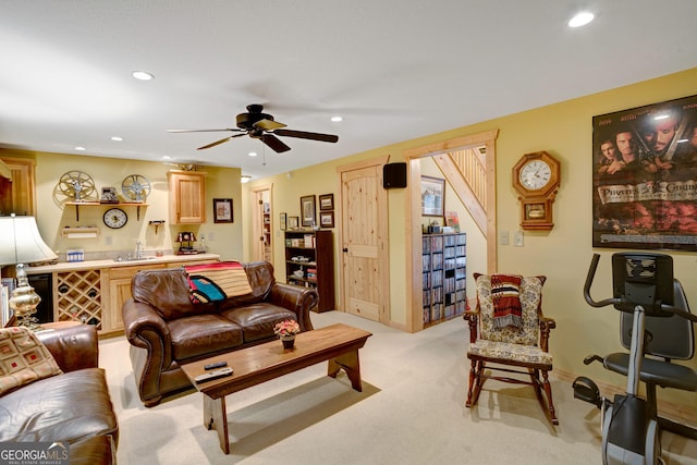 carpeted living room featuring ceiling fan and sink