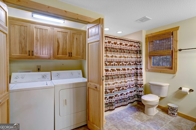 washroom featuring washing machine and clothes dryer, cabinets, and a textured ceiling