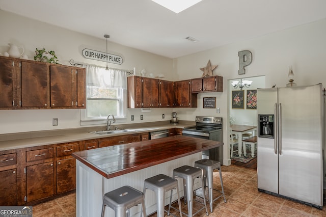 kitchen featuring sink, a center island, hanging light fixtures, stainless steel appliances, and a breakfast bar area