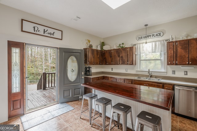 kitchen featuring sink, stainless steel dishwasher, decorative light fixtures, and a kitchen breakfast bar