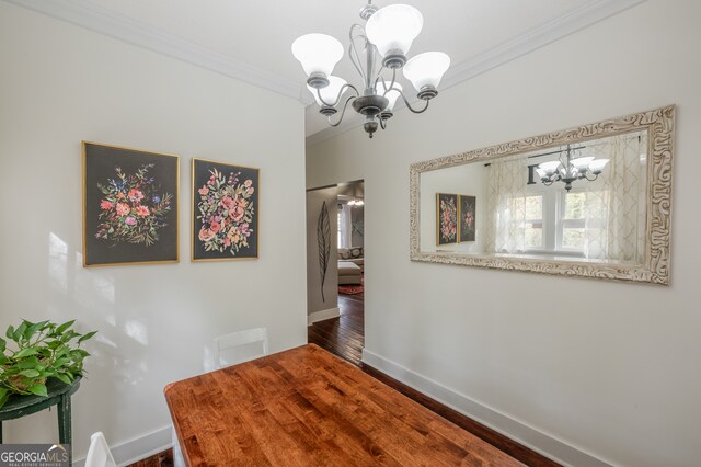 unfurnished dining area with dark wood-type flooring, ornamental molding, and a chandelier