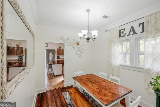 dining area with a notable chandelier, ornamental molding, and dark hardwood / wood-style floors