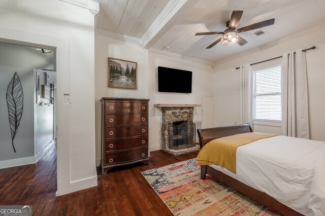 bedroom with a stone fireplace, crown molding, ceiling fan, and dark hardwood / wood-style flooring