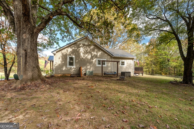 back of property with a wooden deck, central AC, and a yard