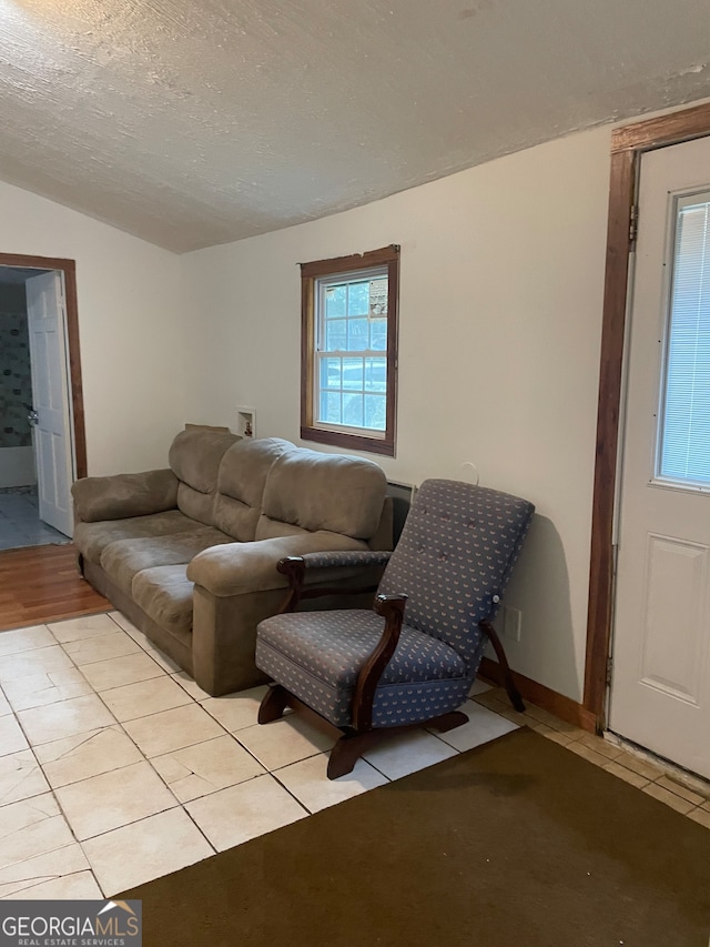 living room featuring lofted ceiling, a textured ceiling, and light tile patterned floors