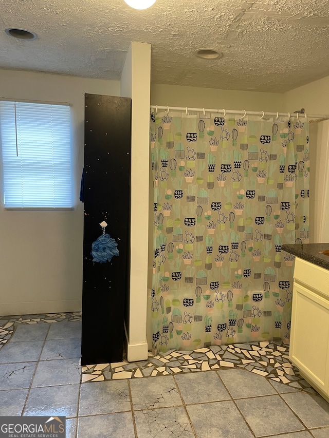 bathroom with vanity, a textured ceiling, and walk in shower