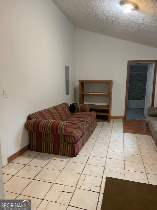 tiled living room featuring lofted ceiling, electric panel, and a textured ceiling