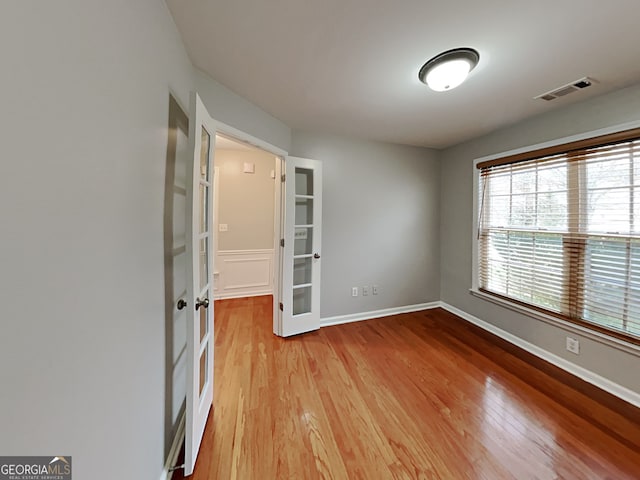 empty room with french doors and light wood-type flooring