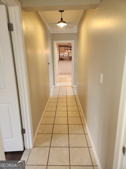 hallway with ornamental molding, baseboards, and light tile patterned floors