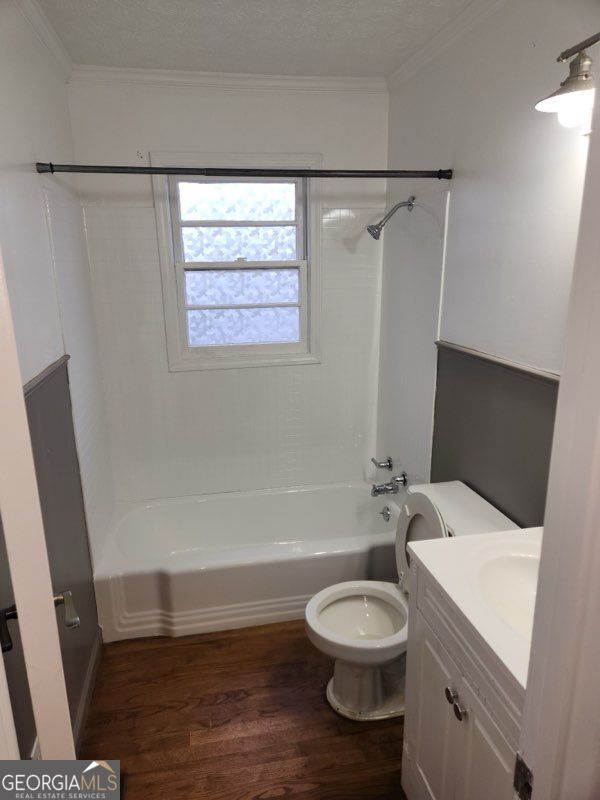 bathroom featuring ornamental molding, tub / shower combination, wood finished floors, and vanity