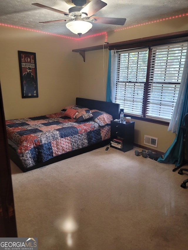 carpeted bedroom featuring ceiling fan and a textured ceiling