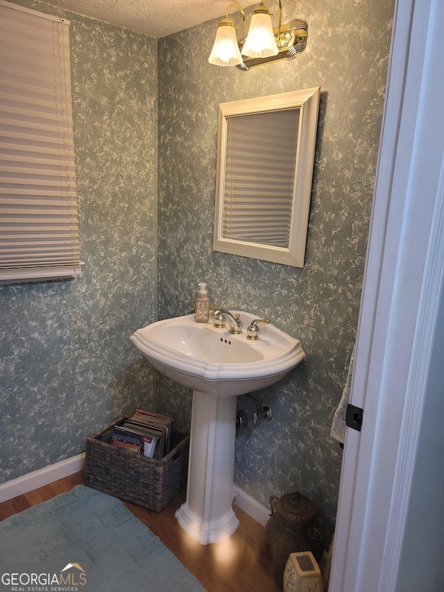 bathroom with hardwood / wood-style flooring, a textured ceiling, and an inviting chandelier