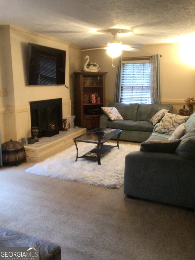 carpeted living room with a textured ceiling, ceiling fan, and ornamental molding