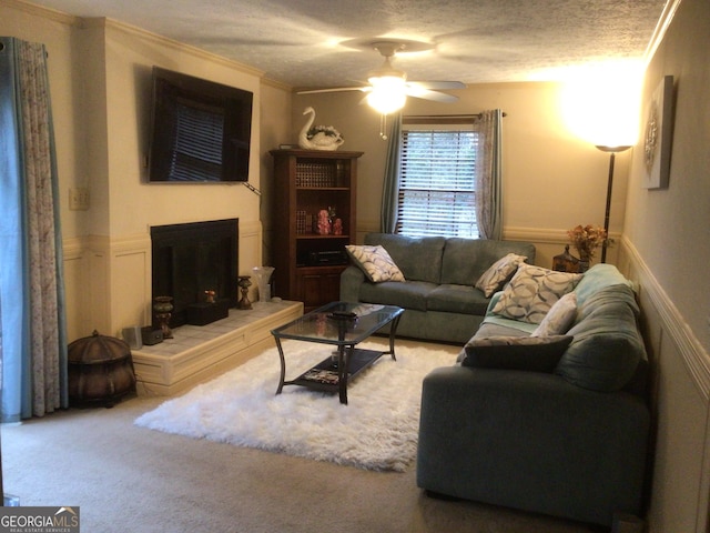 living room featuring a textured ceiling, carpet floors, ceiling fan, and crown molding