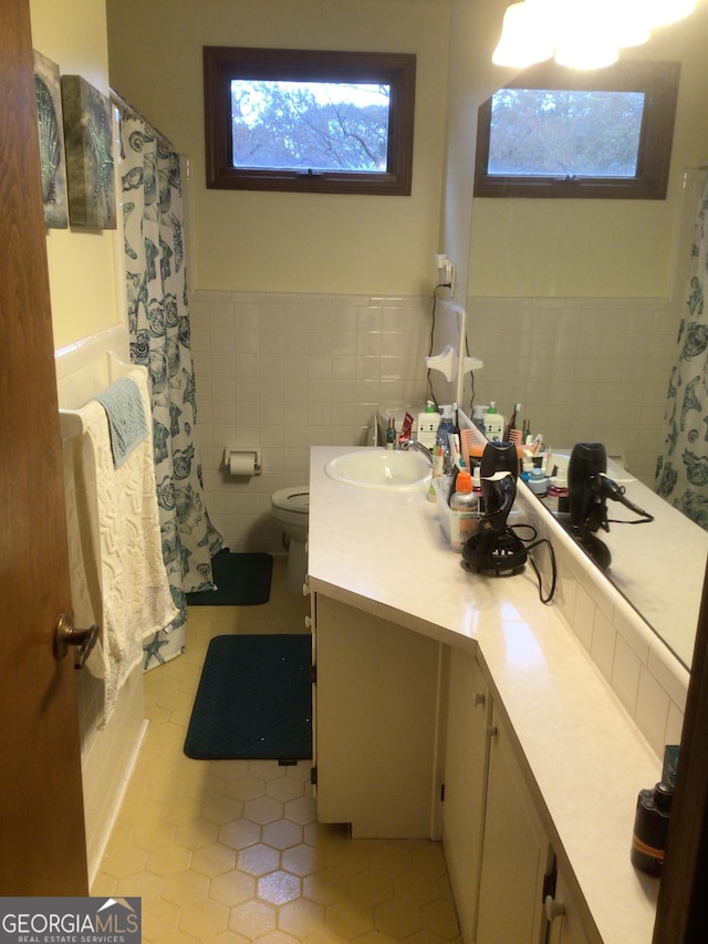 bathroom featuring a shower with shower curtain, vanity, tile walls, tile patterned flooring, and toilet