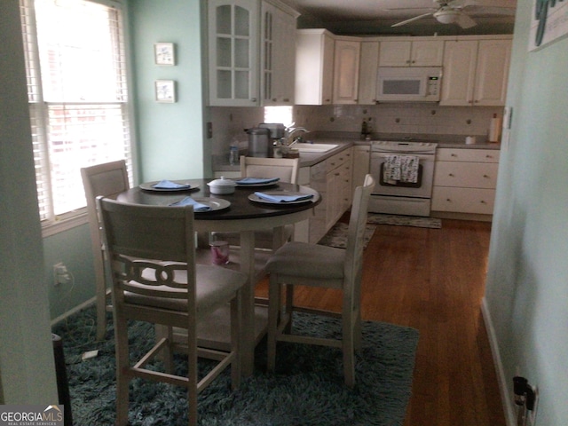 kitchen with white appliances, sink, decorative backsplash, dark hardwood / wood-style flooring, and white cabinetry