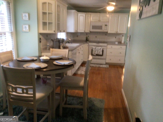 kitchen featuring decorative backsplash, dark hardwood / wood-style flooring, white appliances, sink, and white cabinets