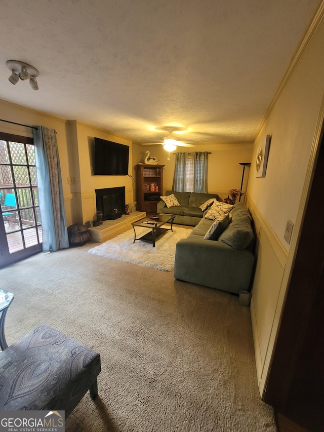 living room with carpet, ceiling fan, crown molding, and a textured ceiling