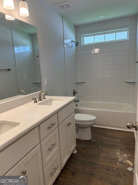 full bathroom with vanity, toilet, wood-type flooring, and tiled shower / bath