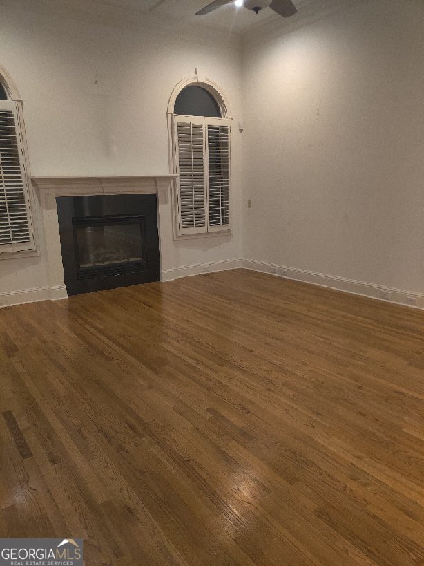 unfurnished living room featuring dark hardwood / wood-style flooring and ceiling fan