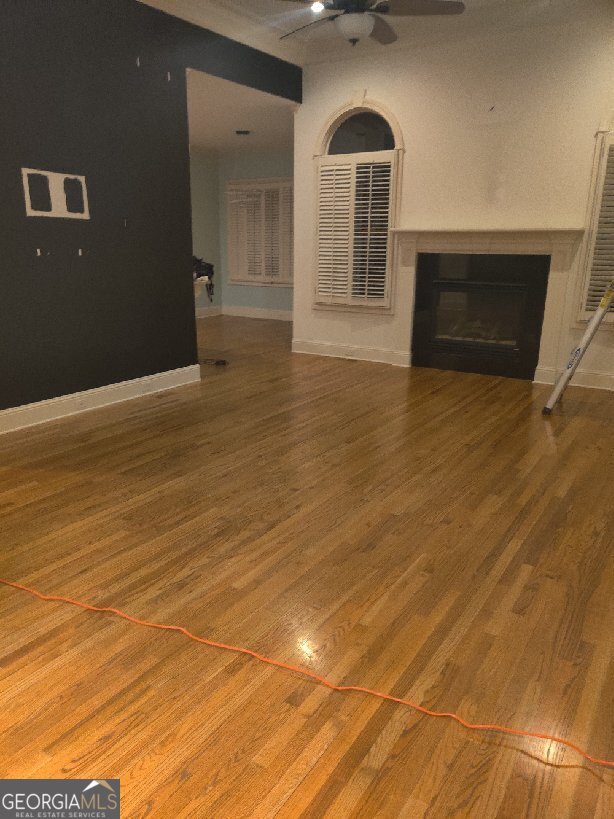 unfurnished living room featuring wood-type flooring and ceiling fan