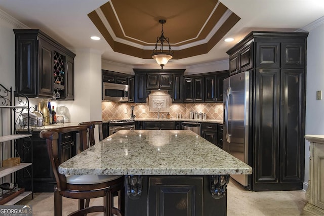 kitchen with a center island, stainless steel appliances, hanging light fixtures, and crown molding