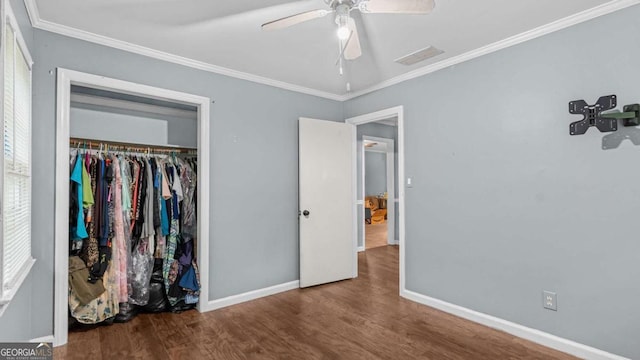 unfurnished bedroom featuring ceiling fan, dark hardwood / wood-style flooring, ornamental molding, and a closet