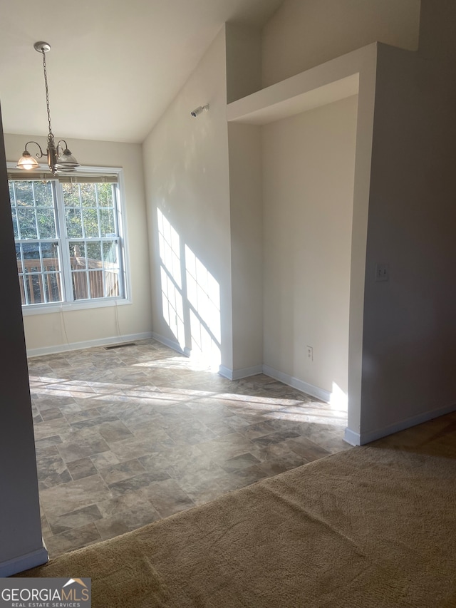 carpeted spare room with a notable chandelier and vaulted ceiling