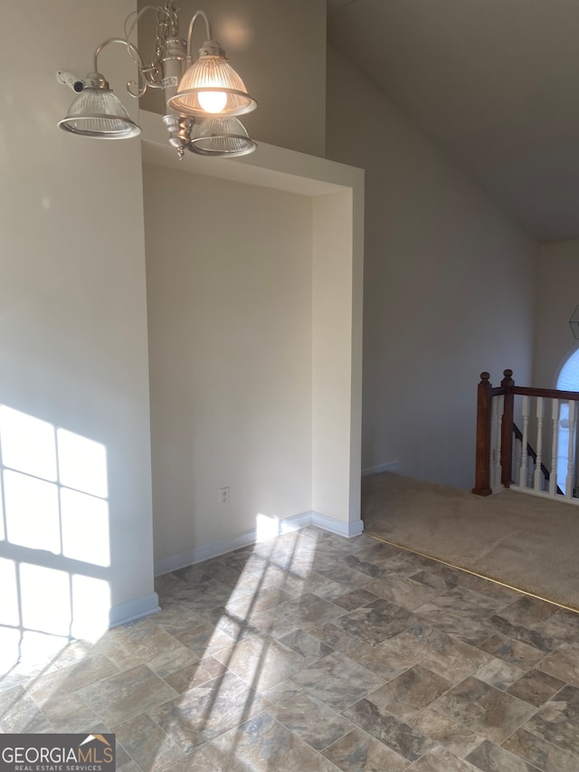 empty room with a chandelier and high vaulted ceiling